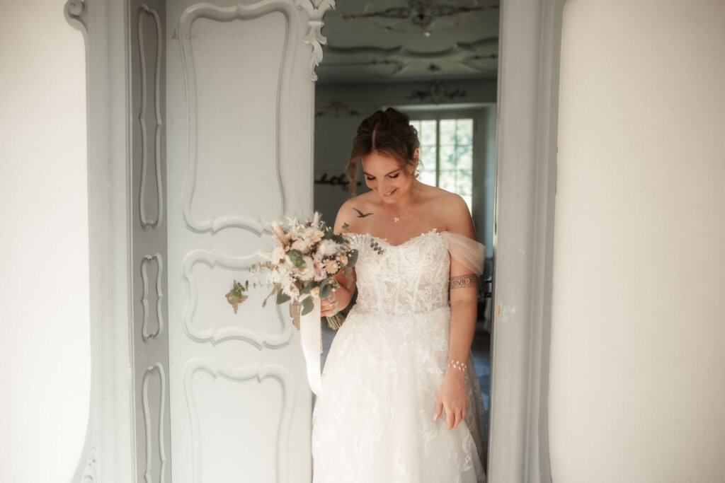 Brautpaar beim First Look im hellen Gang von Schloss Reichenau, Hochzeit Schloss Reichenau