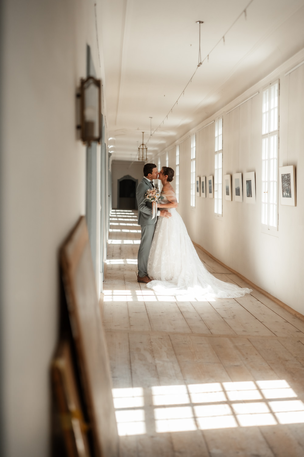 Brautpaar beim First Look im hellen Gang von Schloss Reichenau, Hochzeit Schloss Reichenau