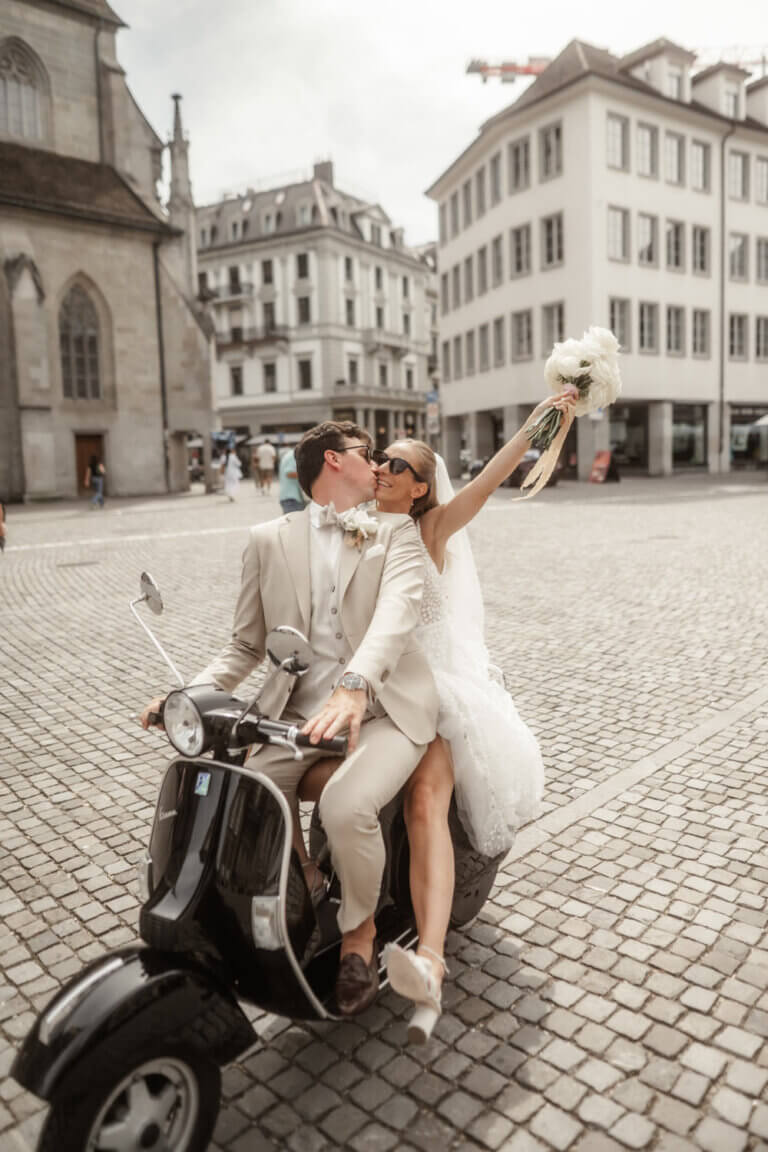 Brautpaar fährt mit einer Vespa durch den Münsterhof in Zürich und ist sehr erfreut