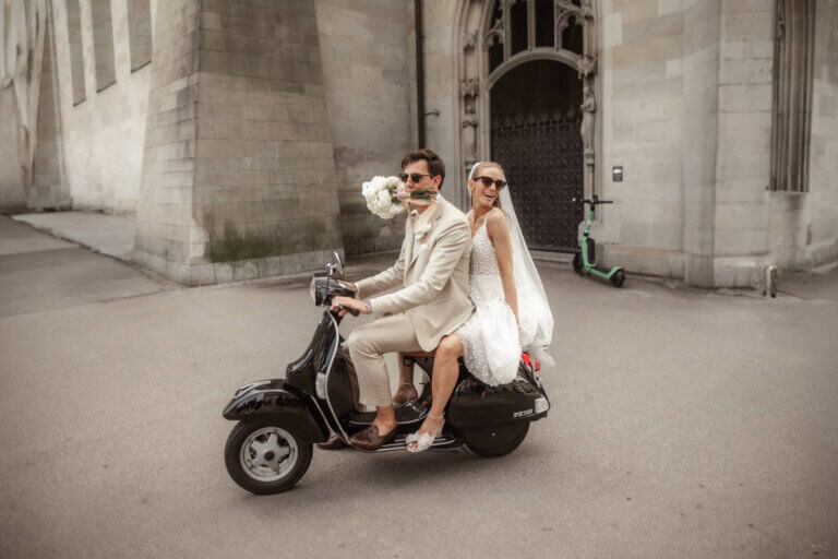 Brautpaar fährt mit einer Vespa durch den Münsterhof in Zürich und ist sehr erfreut